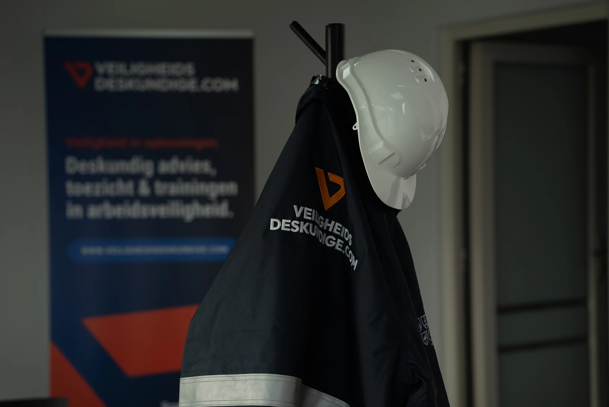 Veiligheidshelm en werkjas van Veiligheidsdeskundige.com aan kapstok